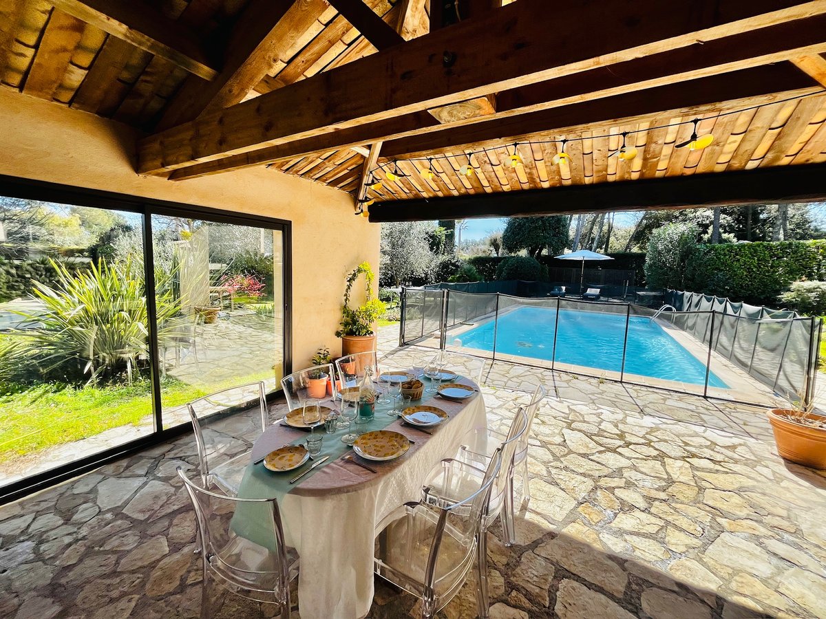 Terrasse couverte avec table dressée et vue piscine